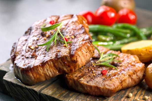 grilled beef steaks on wooden cutting board